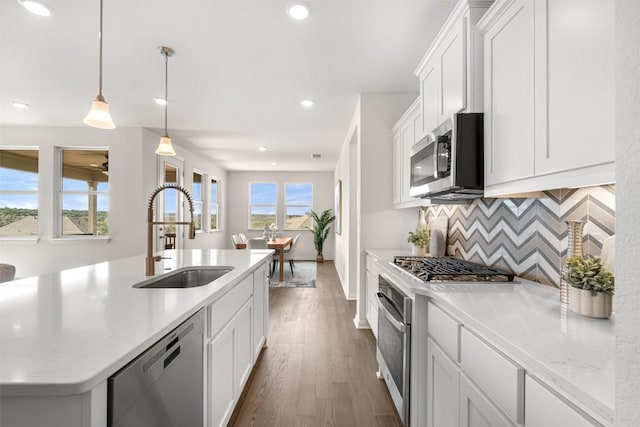 kitchen with dark wood-style flooring, a sink, decorative backsplash, white cabinets, and appliances with stainless steel finishes