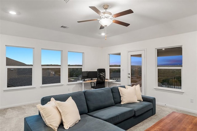 living area with visible vents, light colored carpet, baseboards, and ceiling fan