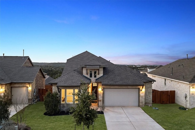 french country home with a garage, a lawn, and a shingled roof