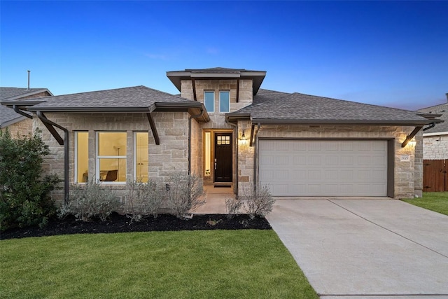 prairie-style home with an attached garage, stone siding, driveway, and a shingled roof