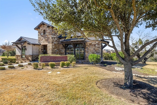 view of front of house with a standing seam roof, a front yard, stone siding, and metal roof