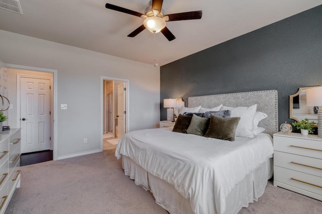 bedroom with visible vents, connected bathroom, baseboards, ceiling fan, and light carpet