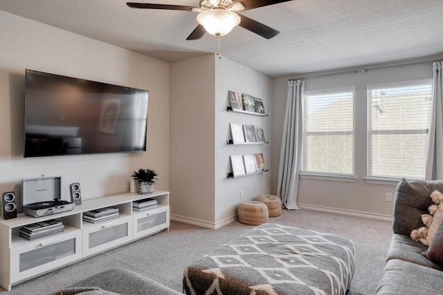 living room featuring a textured ceiling, light colored carpet, baseboards, and ceiling fan