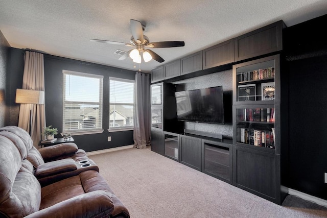 carpeted living room with a textured ceiling, baseboards, and ceiling fan