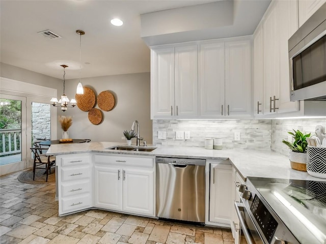 kitchen featuring visible vents, a peninsula, a sink, stainless steel appliances, and white cabinetry