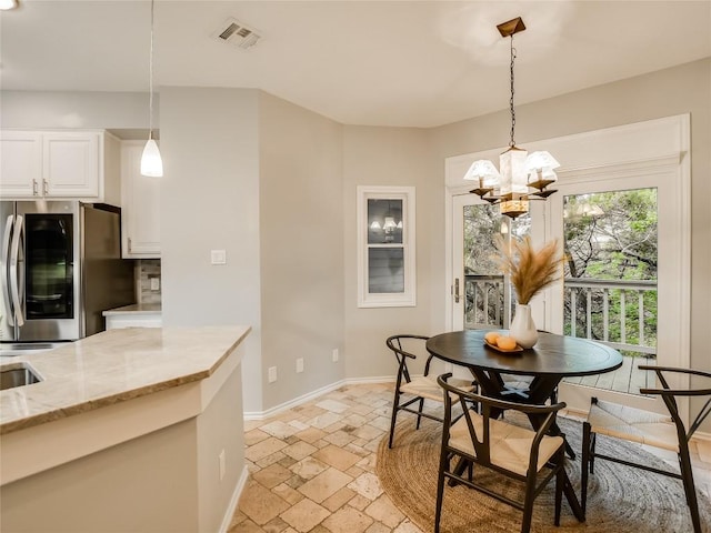 dining room featuring stone tile floors, visible vents, a chandelier, and baseboards