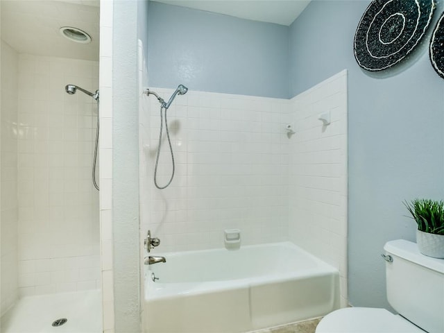 bathroom with toilet and tiled shower / bath combo