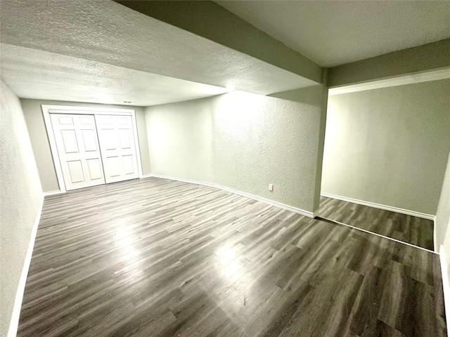 below grade area featuring baseboards, a textured ceiling, and wood finished floors