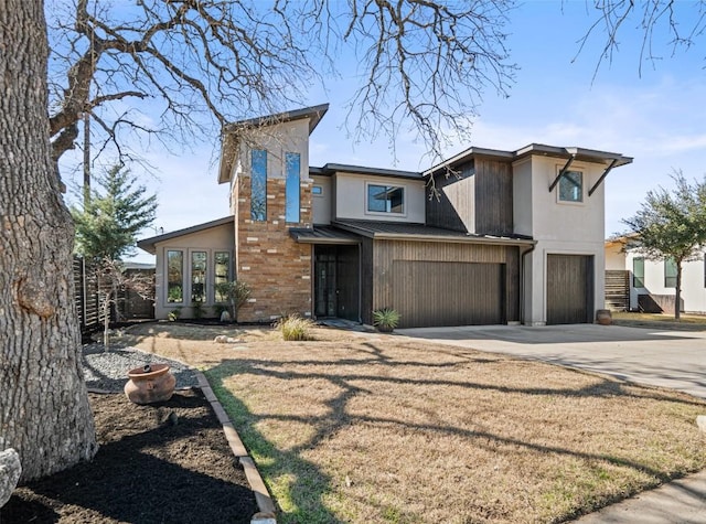view of front of property featuring a garage, stucco siding, driveway, and fence