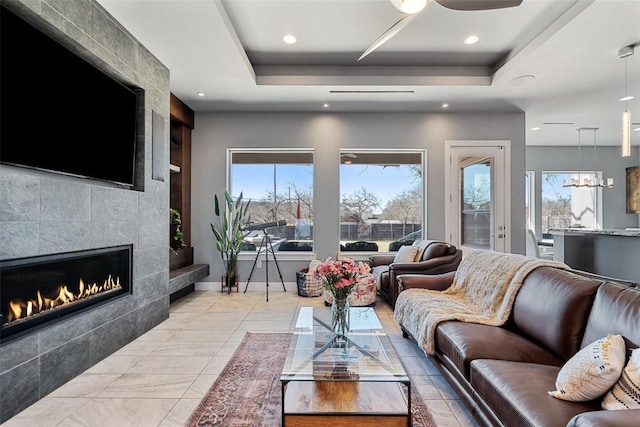 living area with plenty of natural light, a tile fireplace, and a tray ceiling