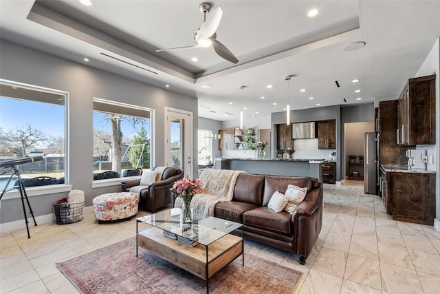 living room with ceiling fan, recessed lighting, and a raised ceiling