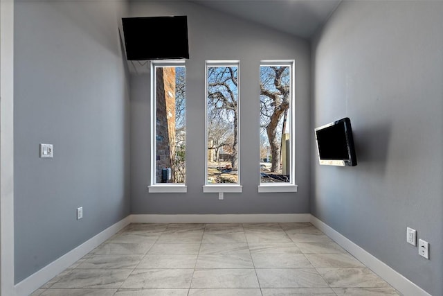 spare room featuring baseboards and vaulted ceiling