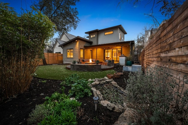 back of property featuring fence, a lawn, and an outdoor fire pit