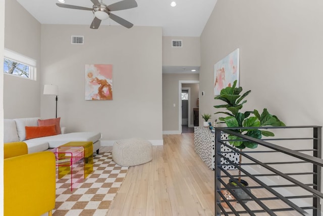 living area with ceiling fan, visible vents, baseboards, and wood finished floors