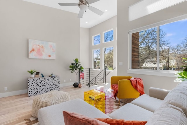 living room with wood finished floors, a towering ceiling, recessed lighting, baseboards, and ceiling fan