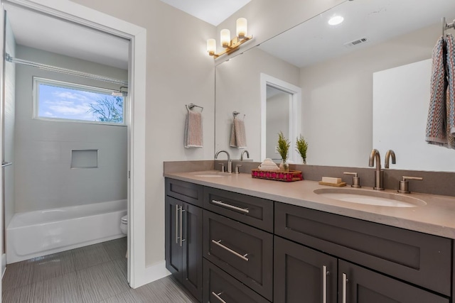 bathroom featuring double vanity, visible vents, toilet, and a sink