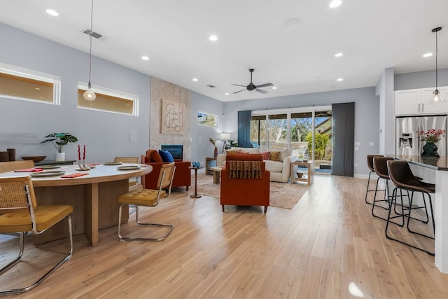 living room featuring a ceiling fan, visible vents, light wood-style flooring, recessed lighting, and a large fireplace