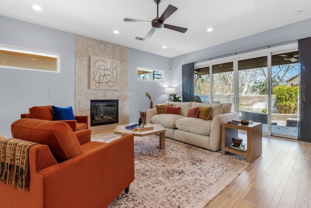 living room with a high end fireplace, recessed lighting, light wood-style flooring, and ceiling fan