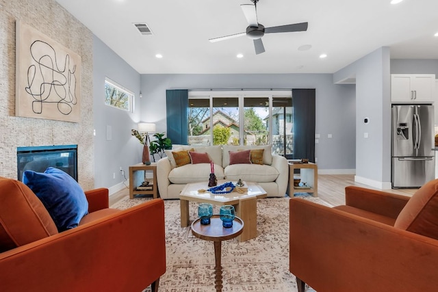 living room featuring a ceiling fan, visible vents, baseboards, recessed lighting, and light wood-style floors