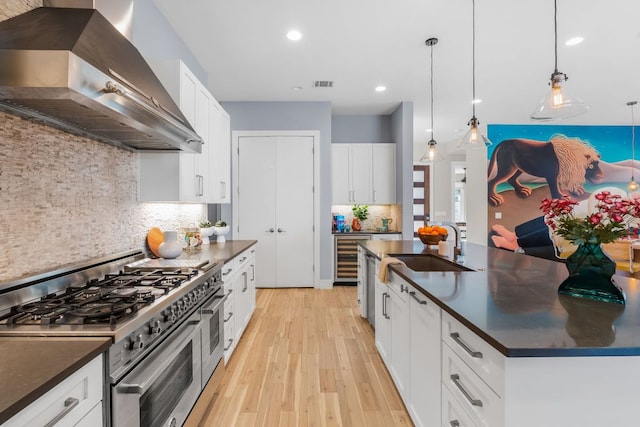 kitchen featuring dark countertops, visible vents, wall chimney range hood, and range with two ovens