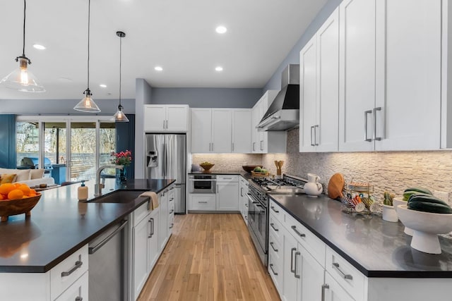 kitchen with a sink, tasteful backsplash, dark countertops, appliances with stainless steel finishes, and wall chimney exhaust hood