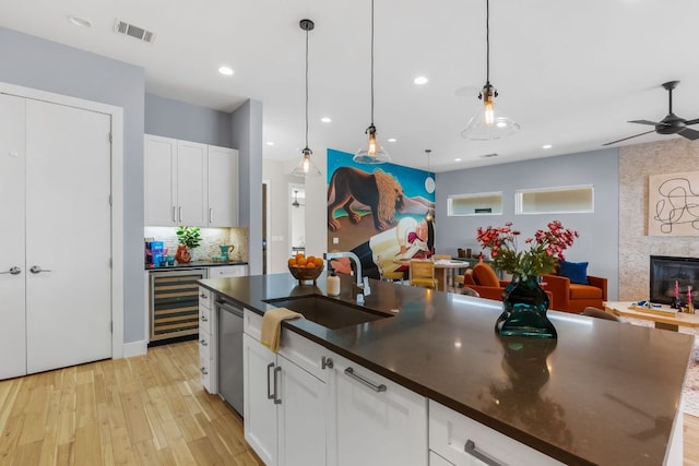 kitchen with visible vents, a sink, dark countertops, open floor plan, and wine cooler