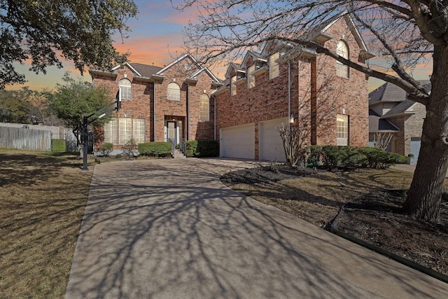 traditional-style house with a garage, fence, brick siding, and driveway