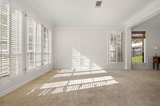 carpeted empty room featuring a decorative wall, visible vents, and ornamental molding