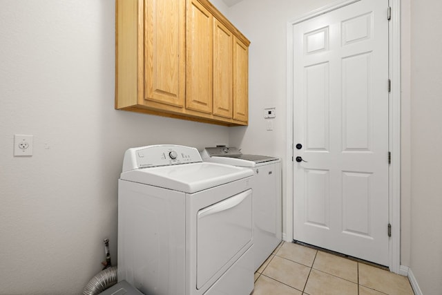 clothes washing area featuring light tile patterned floors, cabinet space, and independent washer and dryer