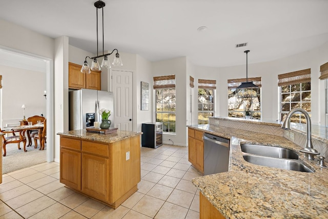 kitchen featuring light tile patterned flooring, a kitchen island, appliances with stainless steel finishes, and a sink