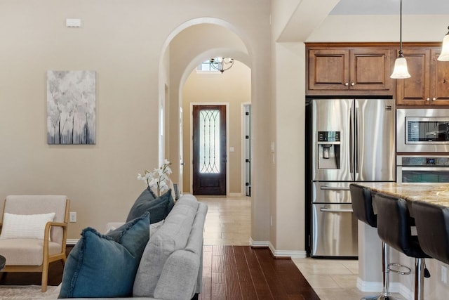 foyer featuring baseboards, arched walkways, and light wood finished floors