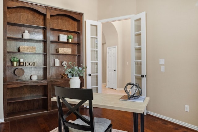 home office featuring dark wood-style floors, arched walkways, and baseboards