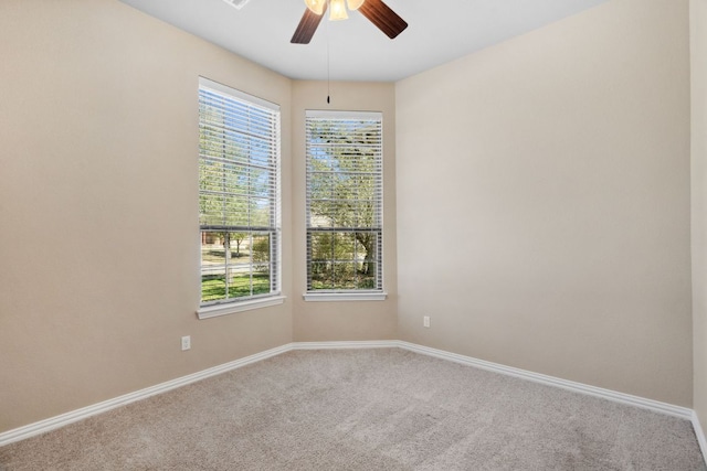 carpeted spare room with a healthy amount of sunlight, baseboards, and ceiling fan