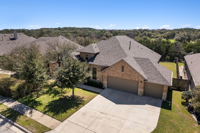 view of front of property featuring brick siding, an attached garage, concrete driveway, and a front lawn