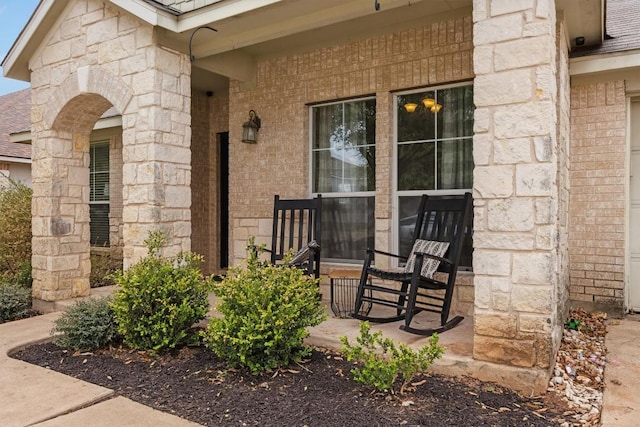 property entrance with brick siding, stone siding, and covered porch