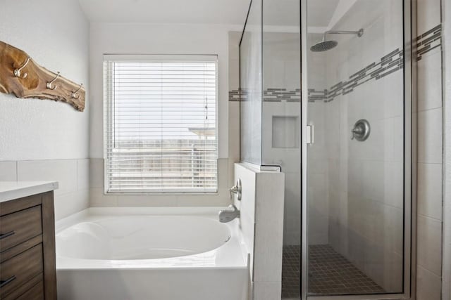 full bathroom with a stall shower, a bath, and vanity