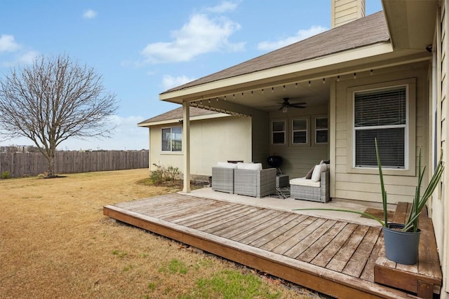 wooden terrace with an outdoor hangout area, a ceiling fan, a yard, and fence