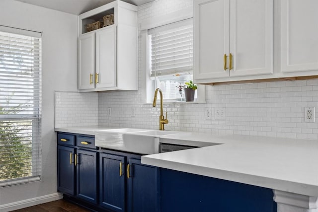 kitchen with light countertops, white cabinets, blue cabinets, and a sink