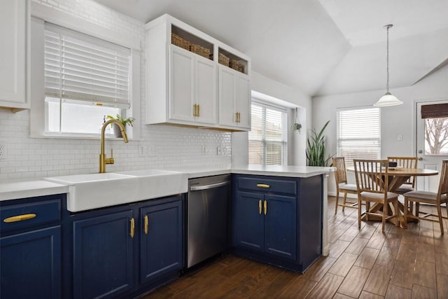 kitchen with blue cabinetry, lofted ceiling, a peninsula, stainless steel dishwasher, and a sink