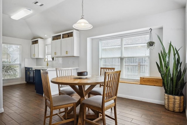 dining area with dark wood finished floors, visible vents, and baseboards