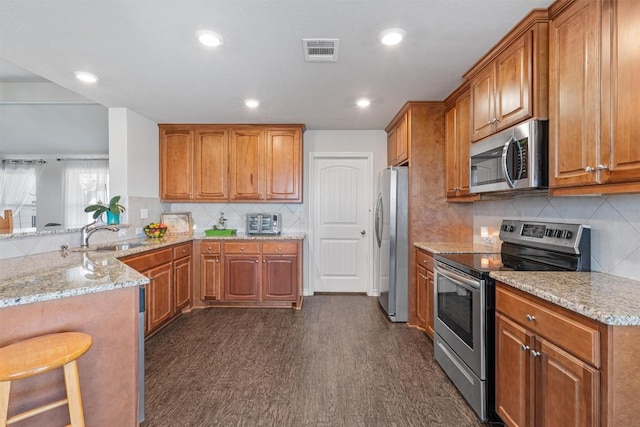 kitchen featuring a sink, light stone countertops, visible vents, and stainless steel appliances