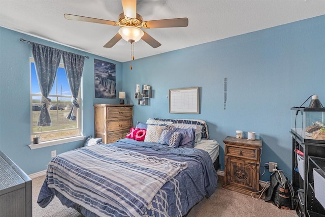 carpeted bedroom with ceiling fan and baseboards