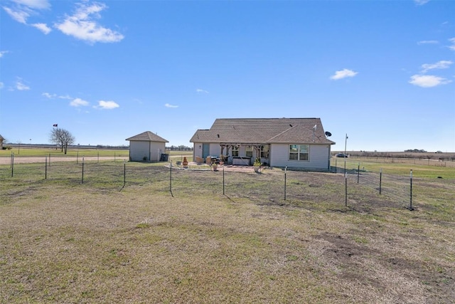 back of property with a storage shed, an outdoor structure, a rural view, and fence