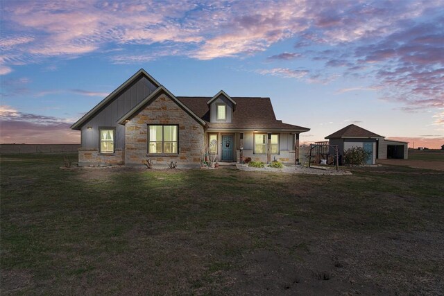 view of front of property featuring an outdoor structure, a front lawn, a garage, stone siding, and board and batten siding