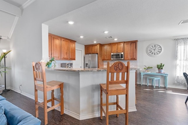 kitchen with a kitchen bar, dark wood-type flooring, visible vents, and appliances with stainless steel finishes