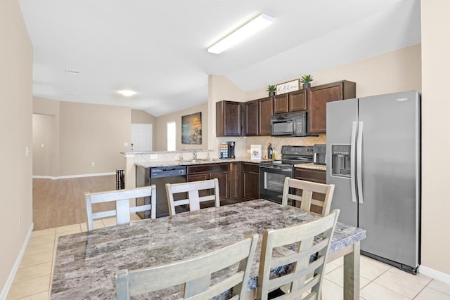 kitchen with tasteful backsplash, dark brown cabinetry, vaulted ceiling, light tile patterned floors, and black appliances