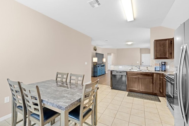 kitchen featuring visible vents, dishwasher, light tile patterned floors, decorative backsplash, and a peninsula