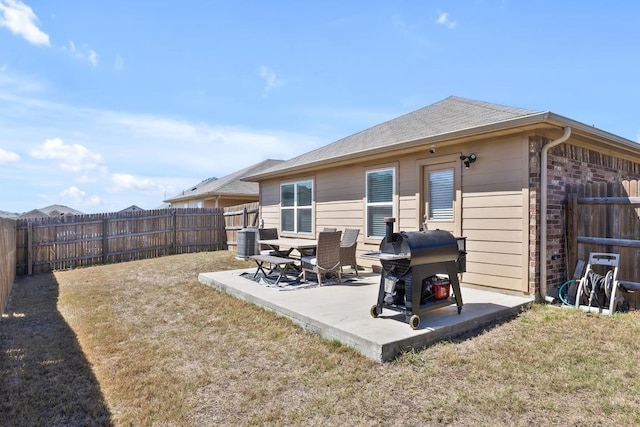 back of house with brick siding, a patio area, a lawn, and a fenced backyard