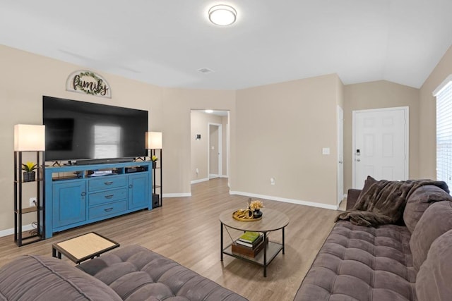 living area with light wood-style flooring, baseboards, and vaulted ceiling