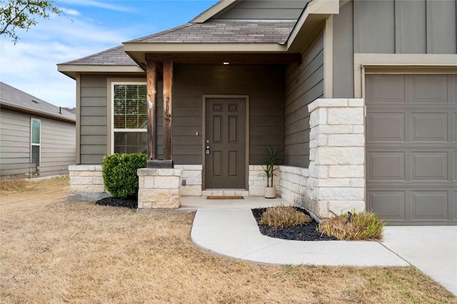 doorway to property with stone siding, an attached garage, and a shingled roof